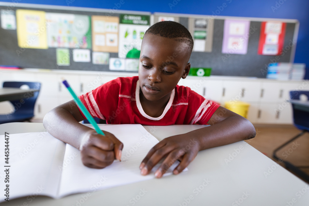 African american boy studying while sitting on his desk in the class at elementary school African american boy studying while sitting on his desk in the class at elementary school