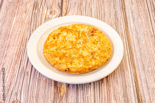 Spanish omelette for one person cooked well curdled on white plate