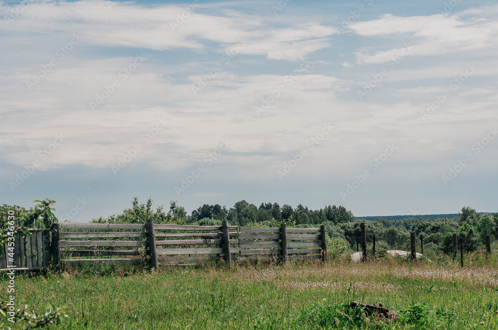 Landscape with old broken wooden fence on dry pasture