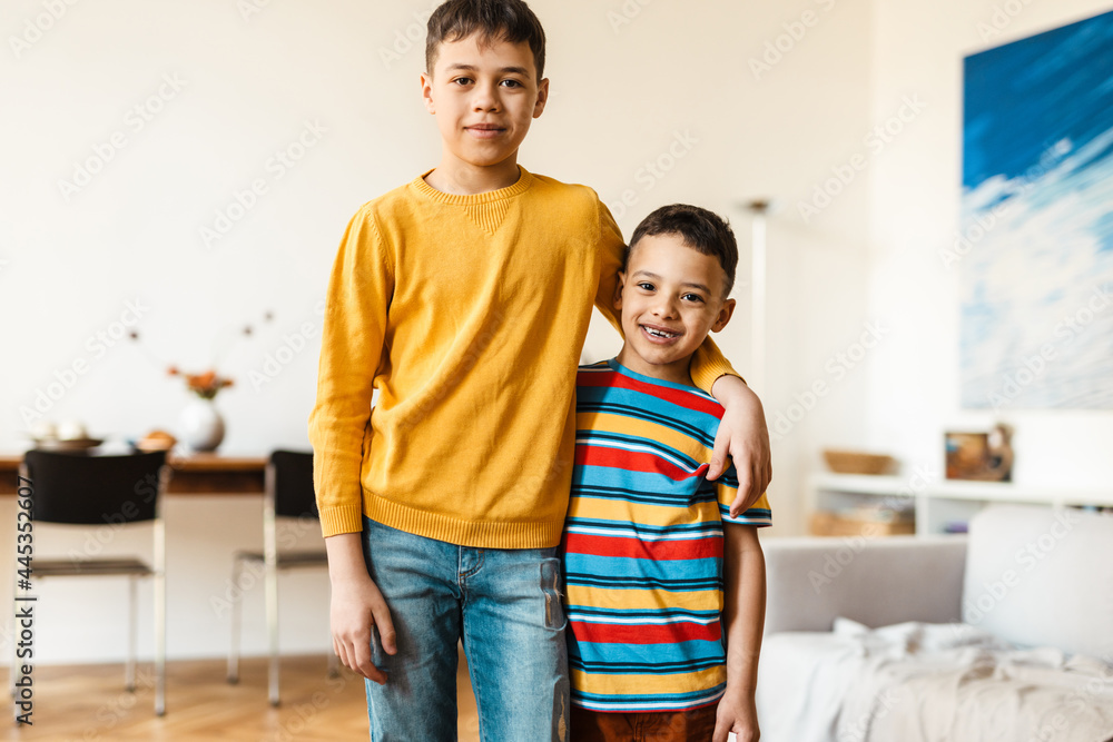 White two boys hugging and smiling at camera while standing at home White two boys hugging and smiling at camera while standing at home