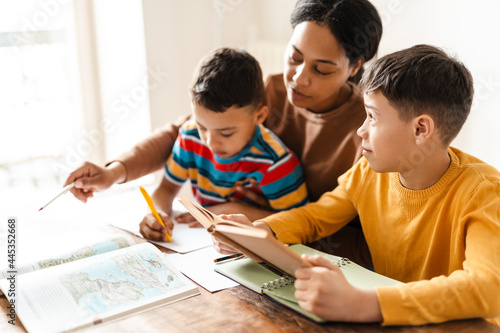 Two boys doing homework with their mother at home