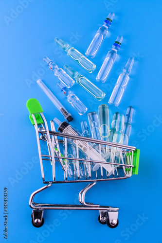 A shop trolley and lots of injection vials on blue. photo