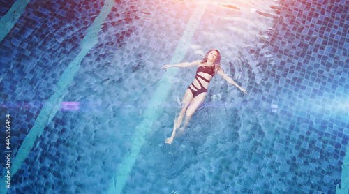 Top view aerial photo of a seductive sexy model in black swimwear is enjoying relax in hotel pool. Amazing fashion woman in bikini having luxury spa rest