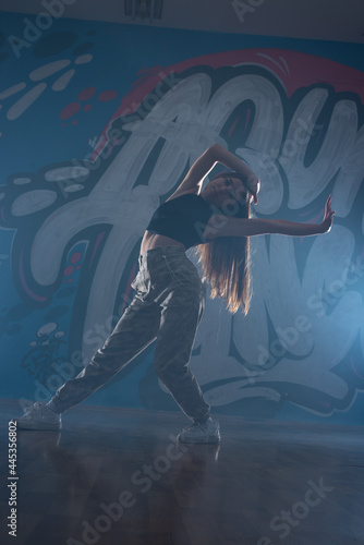 Jumping female dancer against the dark background. Smoke and lights stage setup.