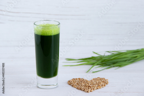 Canvas Print Detox wheatgrass juice in a glass shot and wheat grains on a wooden background