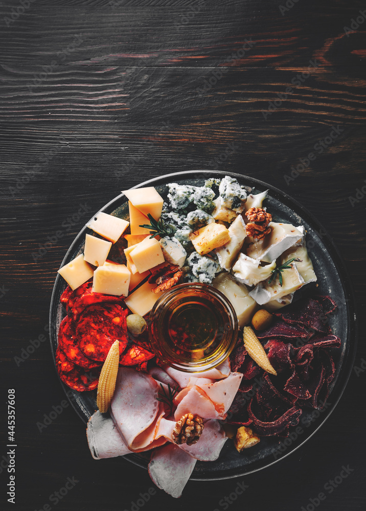 plate with bacon, cheese cubes, meat, salami, ham on wooden table background