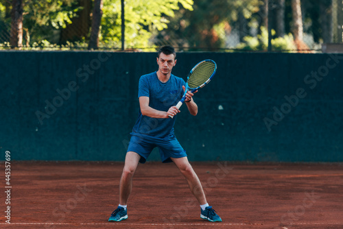 Professional equipped male tennis player beating hard the tennis ball with a backhand © qunica.com