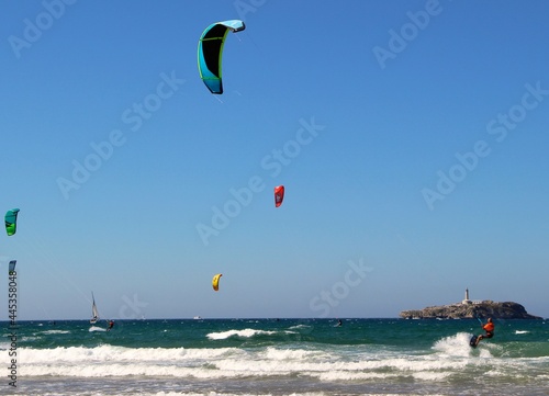 Kitesurfing or kiteboarding from the beach of Somo on a sunny windy afternoon with the Magdalena Palace and Moors Island Santander Cantabria Spain