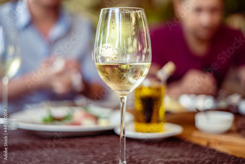 Glass on a high thin leg with white wine in a restaurant
