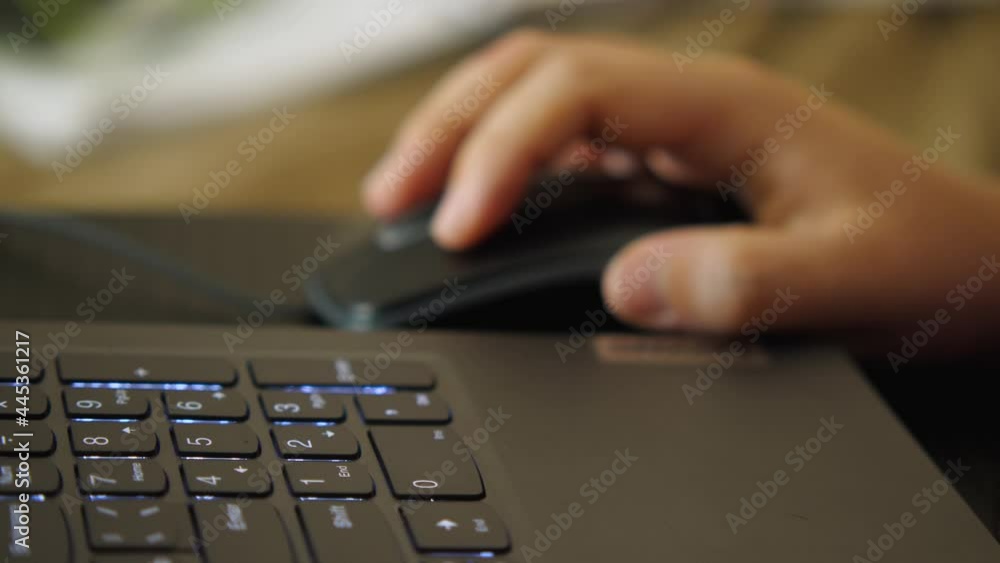 Close-up of the laptop keyboard. In the background, a woman's hand with a computer mouse is out of focus. The concept of remote work from home Close-up of the laptop keyboard. In the background, a woman's hand with a computer mouse is out of focus. The concept of remote work from home