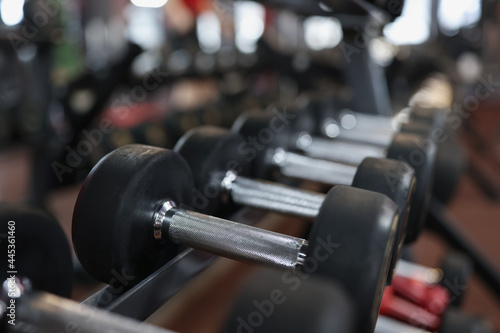 Closeup of many black dumbbells on rack in gym