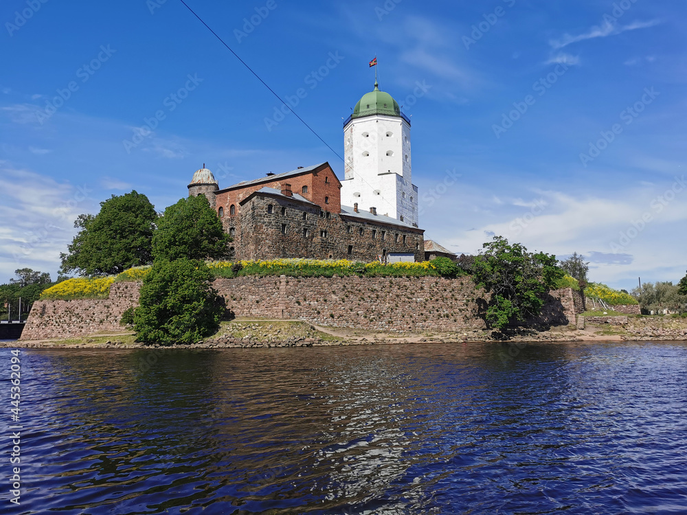 View from the embankment of the Vyborg Castle and the St. Olaf Tower, built in the 13th century, in the city of Vyborg against the blue sky.