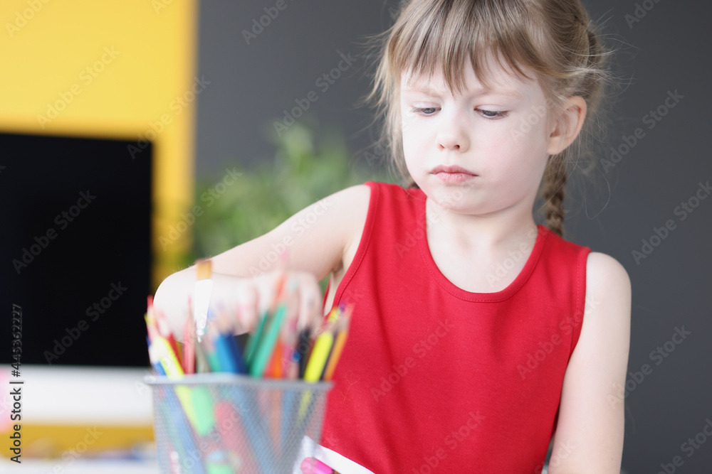 Little girl taking multicolored pencil from container Little girl taking multicolored pencil from container