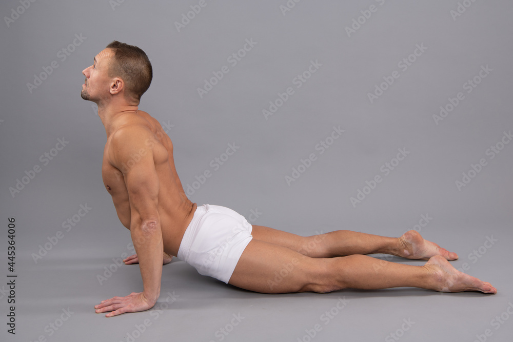 Obraz premium Yogi man do back-bending asana cobra yoga pose grey background, body position