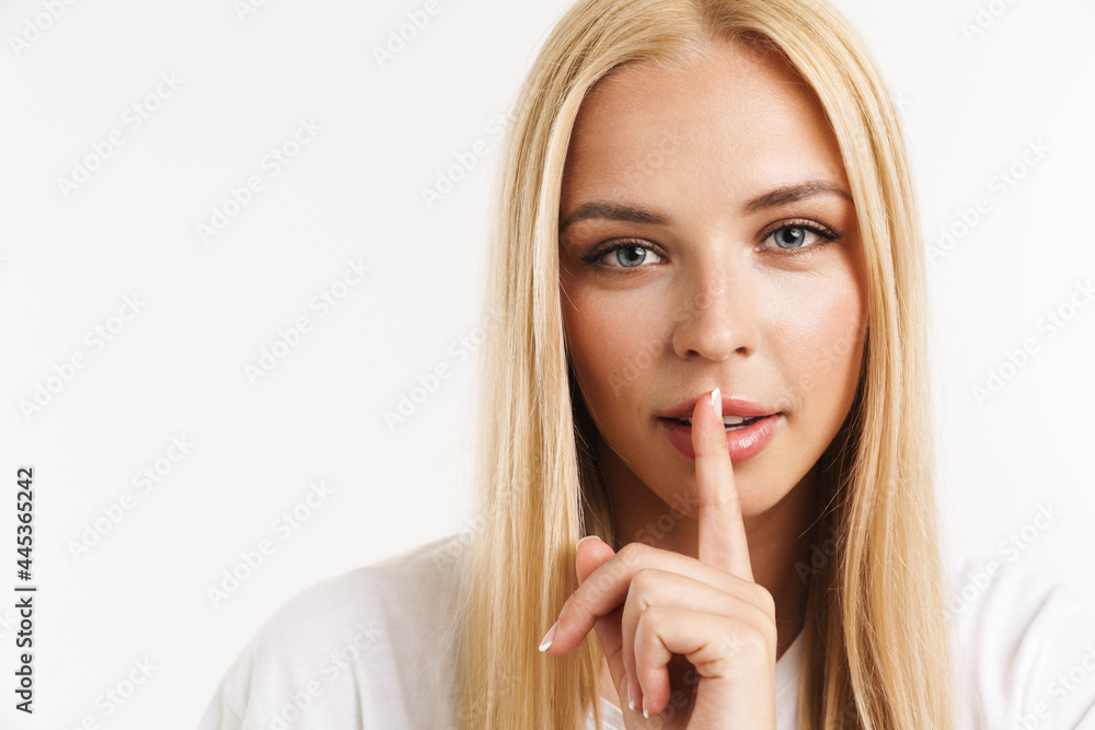 Young blonde woman in t-shirt showing silence gesture at camera Young blonde woman in t-shirt showing silence gesture at camera