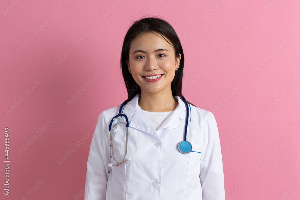 Asian positive doctor woman in white medical gown with stethoscope against pink background portrait Asian positive doctor woman in white medical gown with stethoscope against pink background portrait