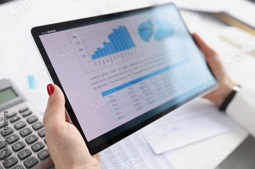 Woman holding digital tablet with charts in her hands closeup