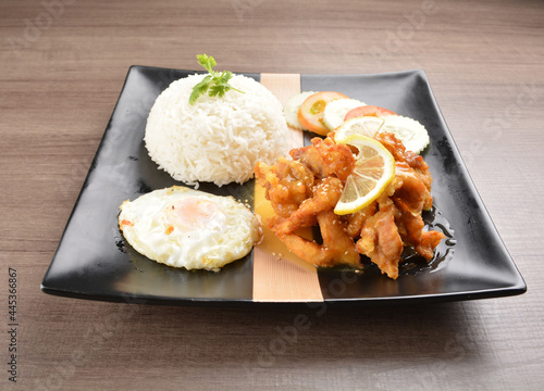 stir fried chicken meat in lemon sour sauce with white rice and fried egg on wood background asian halal set lunch menu