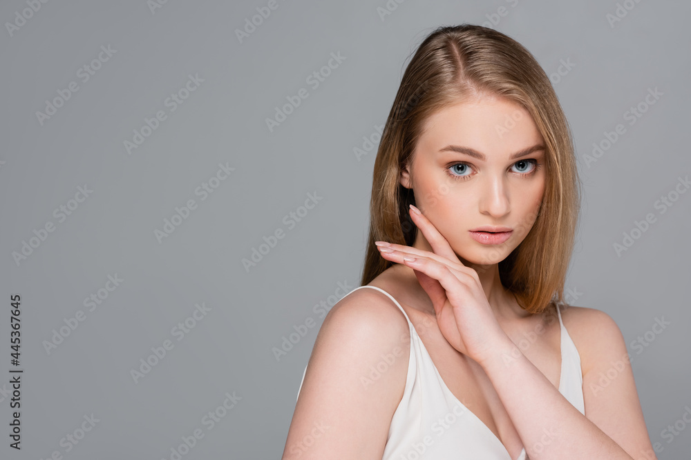 young pretty woman with makeup looking at camera isolated on gray