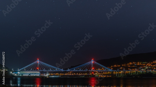 illuminated bridge over the sea bay and sky night and stars with city in background