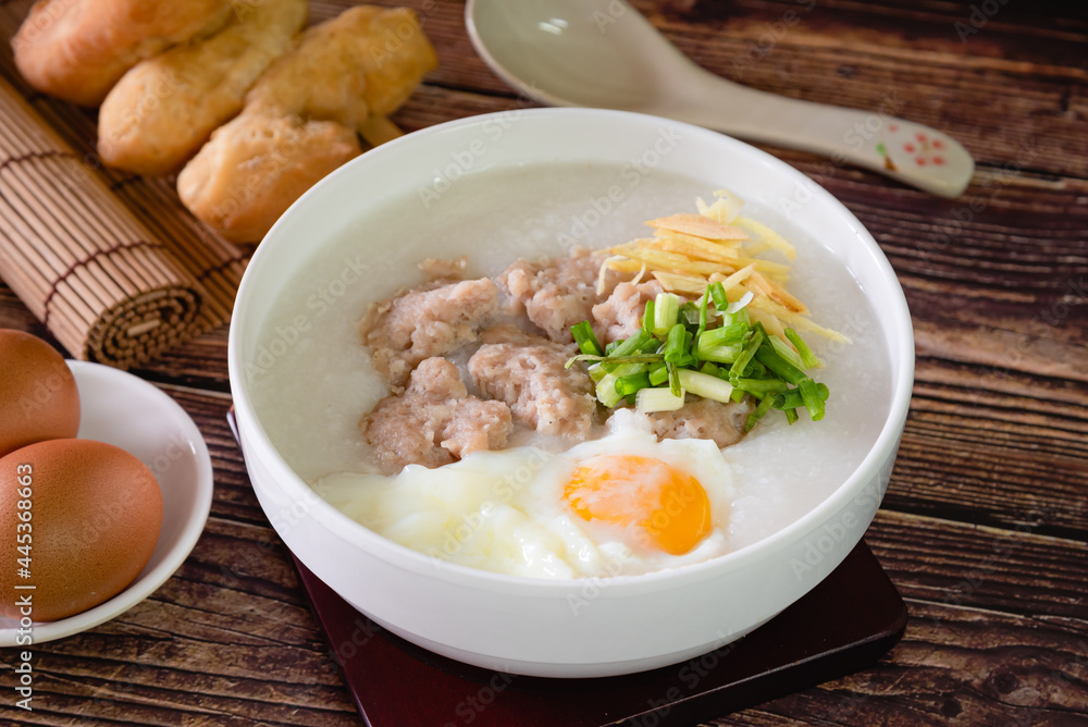 pork ball and boiled egg on top Chinese rice porridge (congee) as Asian breakfast on wooden background pork ball and boiled egg on top Chinese rice porridge (congee) as Asian breakfast on wooden background