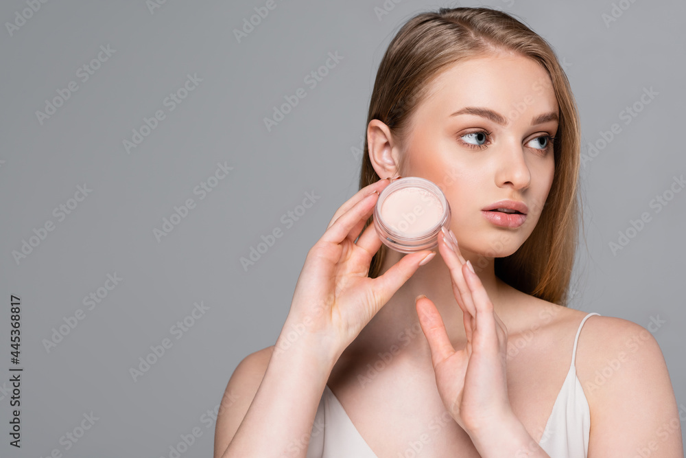 young woman holding face powder container isolated on grey young woman holding face powder container isolated on grey