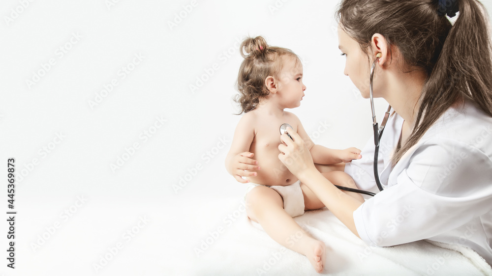Pediatrician examines one-year-old baby girl. Doctor using stethoscope to listen to child checking heart beat. copy space Pediatrician examines one-year-old baby girl. Doctor using stethoscope to listen to child checking heart beat. copy space