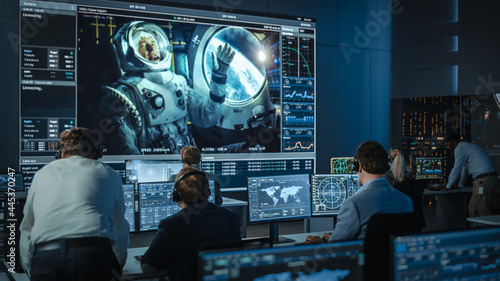 Group of People in Mission Control Center Establish Successful Video Connection on a Big Screen with an Astronaut on Board of a Space Station. Flight Control Scientists Sit in Front of Computers. photo