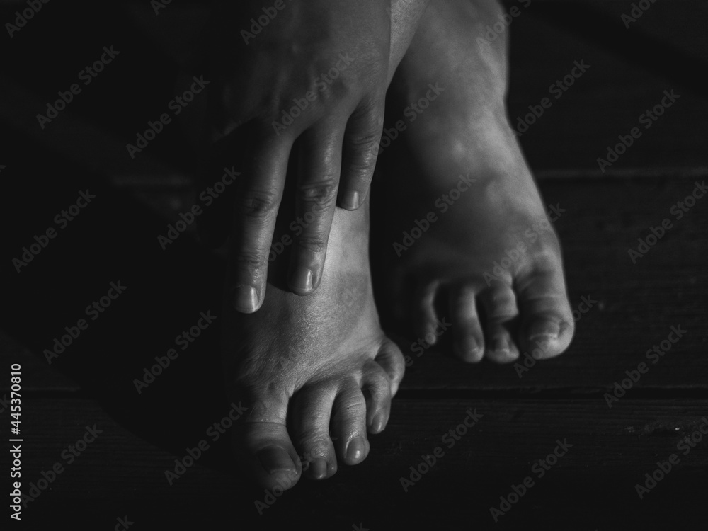 Fototapeta premium bare woman feet and hand on the wooden floor, human body parts in closeup
