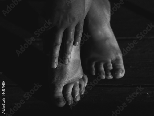 bare woman feet and hand on the wooden floor, human body parts in closeup