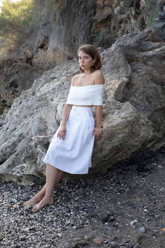 Natural beauty of as young lady Posing in the shore of the coast side in a tourist location with rocks background