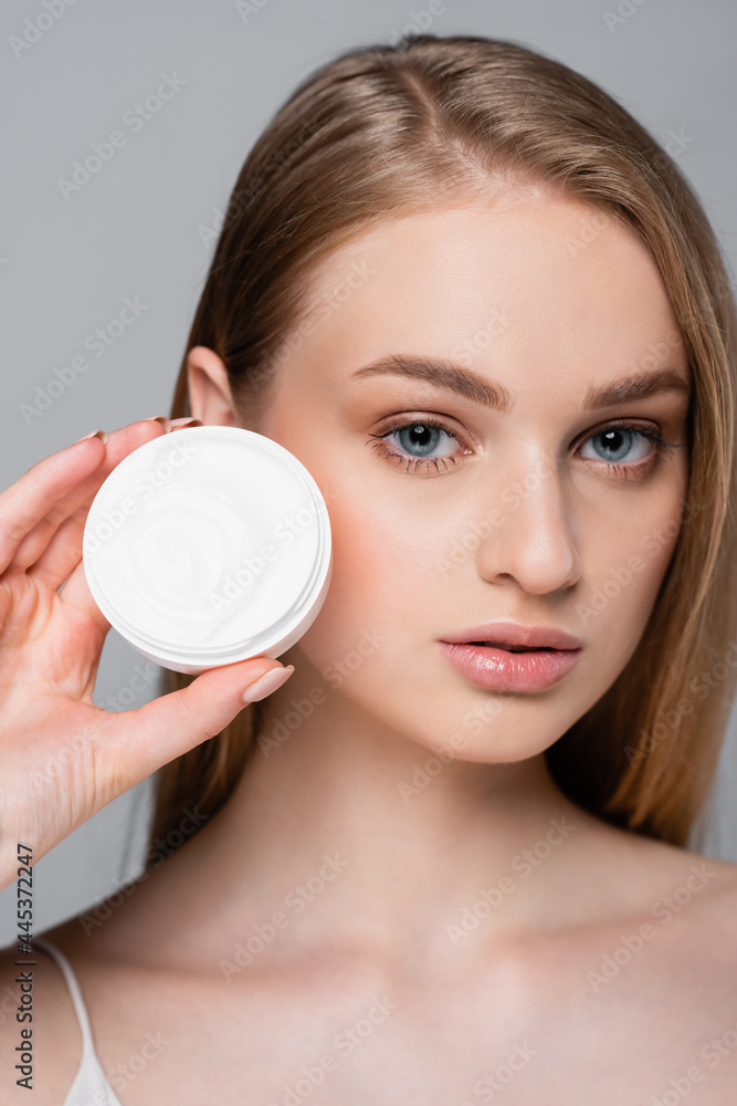 pretty young woman holding container with face cream isolated on grey pretty young woman holding container with face cream isolated on grey
