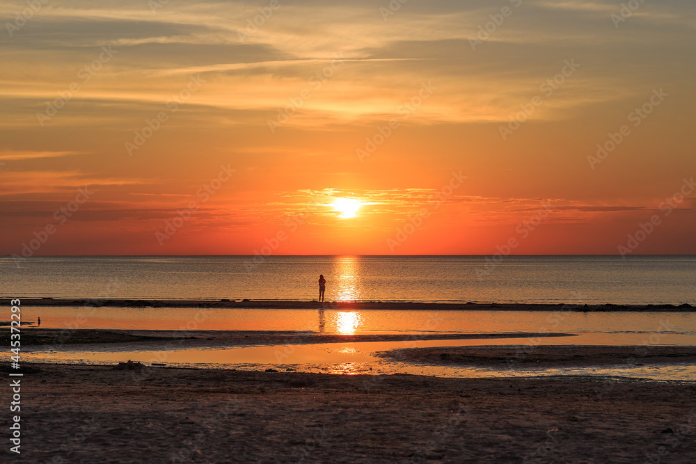 orange sunset in the evening on the baltic sea and silhouette of a man
