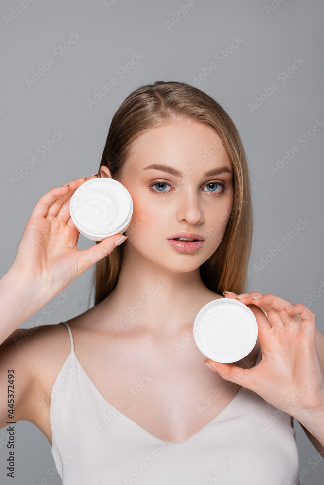pretty young woman holding container with cosmetic cream isolated on grey pretty young woman holding container with cosmetic cream isolated on grey