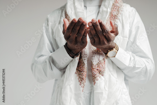 Close up photo. Hands of arab man in white shirt folded together while praying in mosque