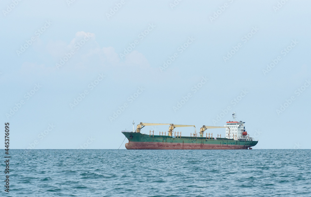 Large ship with crane unloading in the ocean with blue sky landscape,Cargo ship concept in the industrial sea