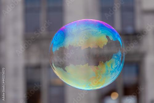 Selective focus of colourful bubbles floating in the air, Rainbow soap foam with reflection of building around Dam Square in the ball as background, Amsterdam, Netherlands.