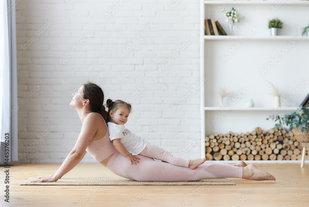 Obraz premium Side view of a young woman practicing yoga, lying in Cobra pose