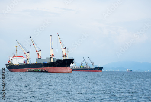 Big crane in the industrial ship in the ocean and mountain in island background,Transportation ship in economy sea concept landscape