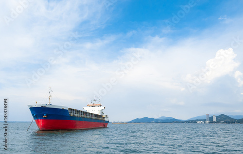 Cargo ship red blue color in the ocean and island mountain background with the blue sky and cloudy landscape