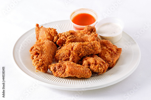 Fried chicken wings with sauce in a white plate on a white background