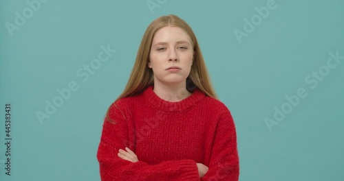 Pretty young woman with long blond hair holding arms across expressing emotion of doubt and distrust
 photo