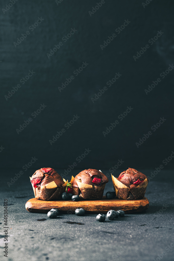 Muffin. Chocolate muffins with stawberry. Muffins on wooden stand. - obrazy, fototapety, plakaty 