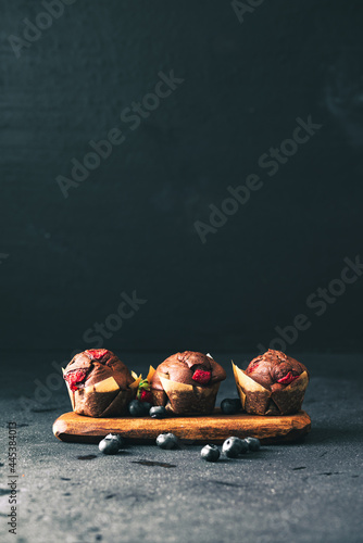 Muffin. Chocolate muffins with stawberry. Muffins on wooden stand. © Exploder