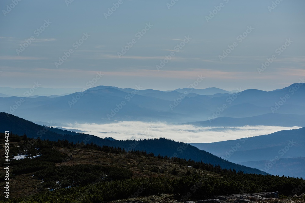 Mountain landscape at dawn. The valley is filled with fog at dawn. The tops of the mountains are visible