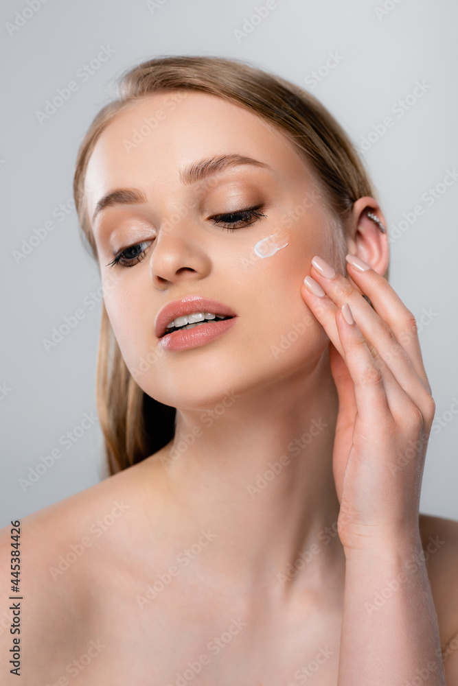 pretty woman applying cream on face isolated on grey pretty woman applying cream on face isolated on grey