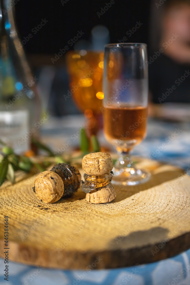 Glass of champagne with two broken corks lay on wooden board on table Glass of champagne with two broken corks lay on wooden board on table