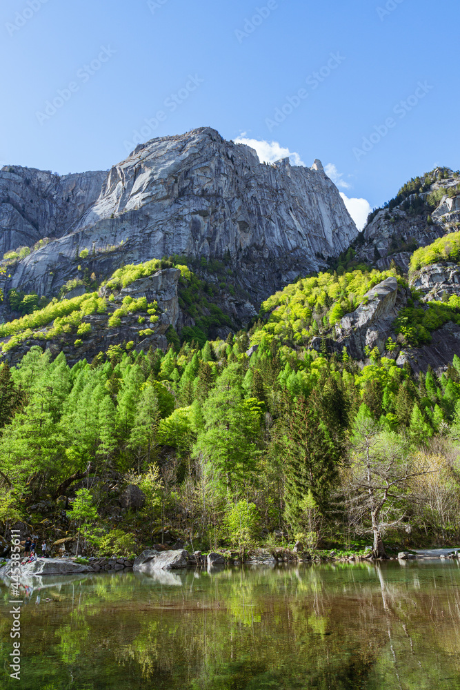 A small alpine lake during spring in val di mello, among the Italian alps, near the town of San Martino, Italy - may 2021