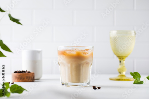 Cold coffee with ice and cream on a white tile background. Homemade cold latte. 