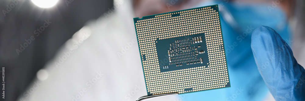 Researcher holds small microcircuit with tongs closeup Researcher holds small microcircuit with tongs closeup